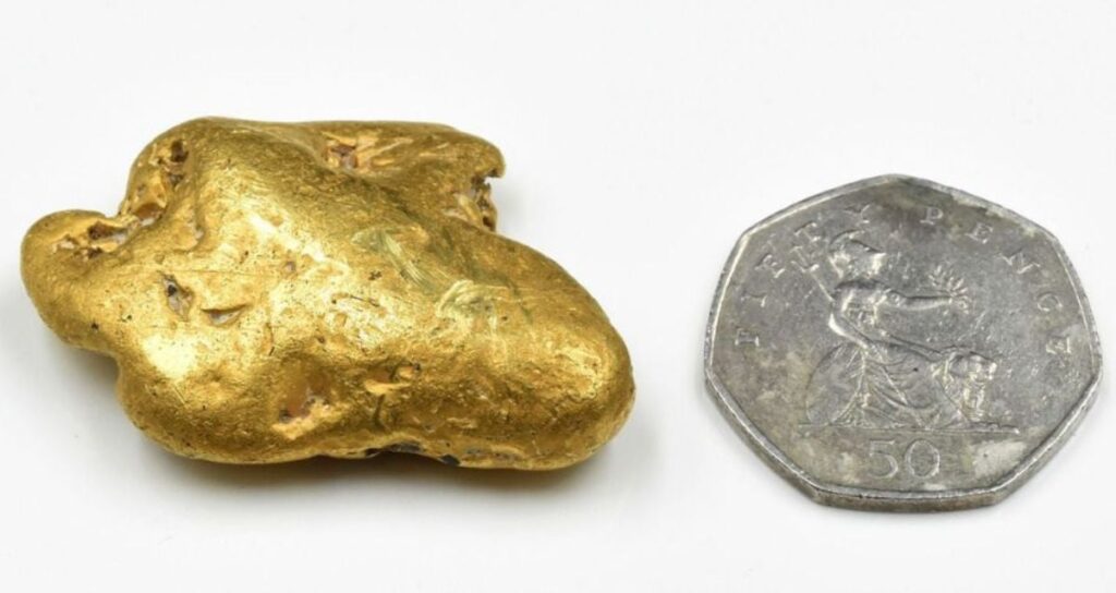 Gold Nugget Alongside Coin Featured