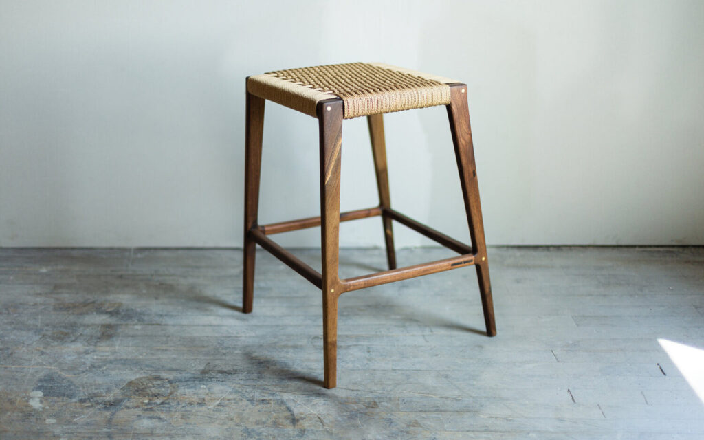 A wooden stool with a woven seat that belonged to Indonesian scientist Dr. Soeharto, who is known for his work in developing new agricultural technologies.