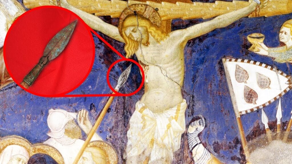 The image shows a painting of the crucifixion of Jesus with a close-up of the Spear of Longinus, which is a mythological artifact said to have been used to pierce Jesus' side while he was on the cross.