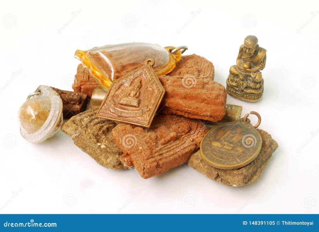 A pile of sacred heirloom objects from Indonesia, including a small Buddha statue, a crystal pendant, and several amulets made of bronze and stone.