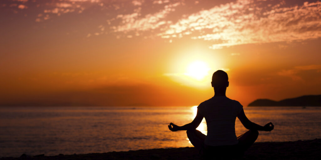 The image shows a person meditating in a peaceful environment to sharpen the power of their mind for spiritual awakening and inner peace.