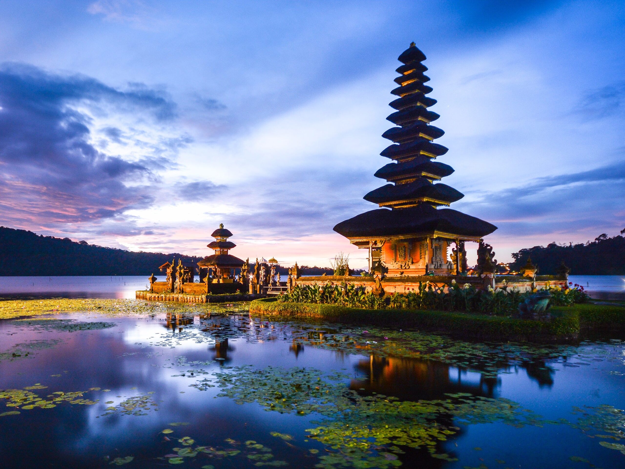 The image shows Pura Ulun Danu Bratan, a Balinese Hindu temple located on the shores of Lake Bratan in Bali, Indonesia. The temple is a popular tourist attraction due to its stunning setting and unique architecture.
