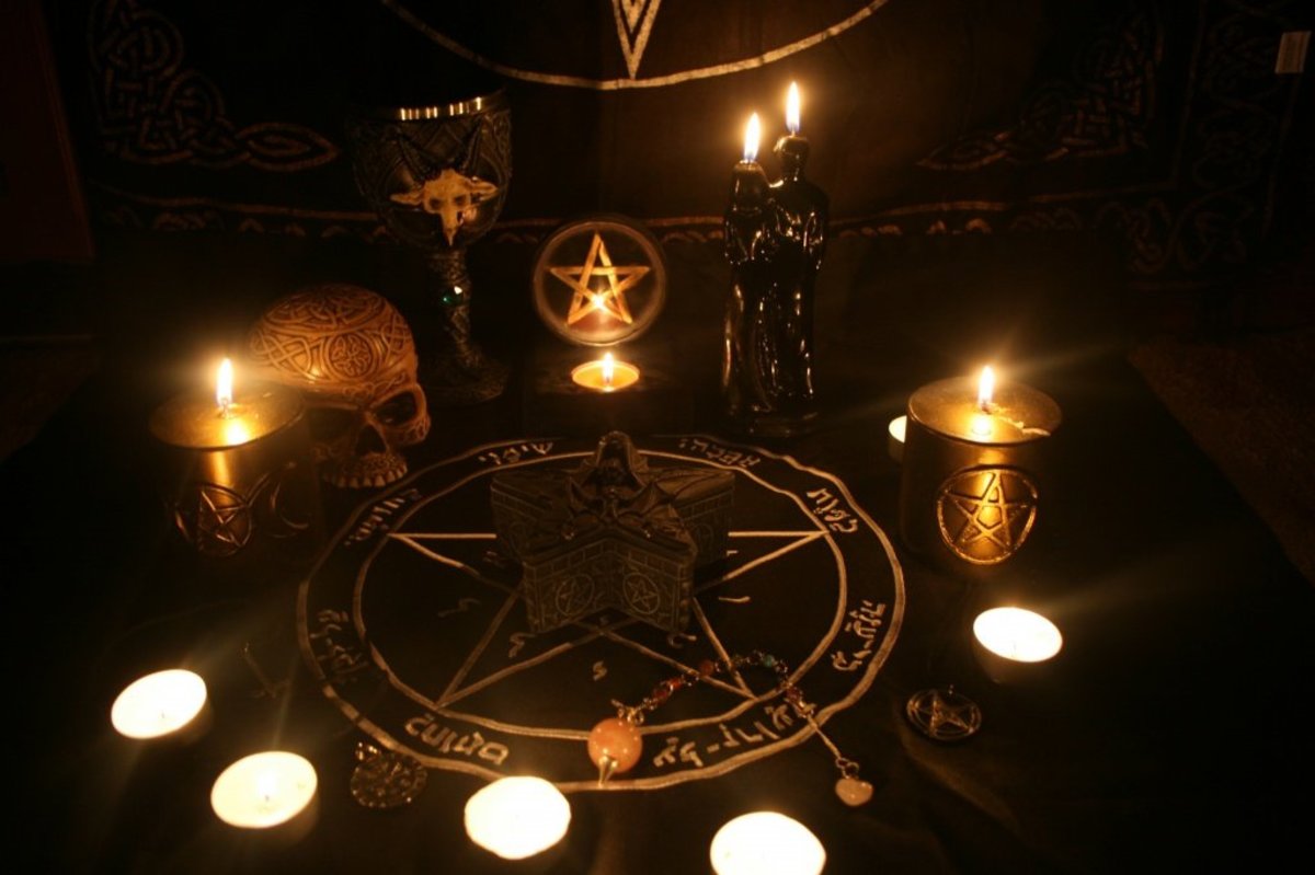 An illustration of a table set up for a ritual, with candles, a skull, and other objects, to explain the differences between witchcraft and black magic.
