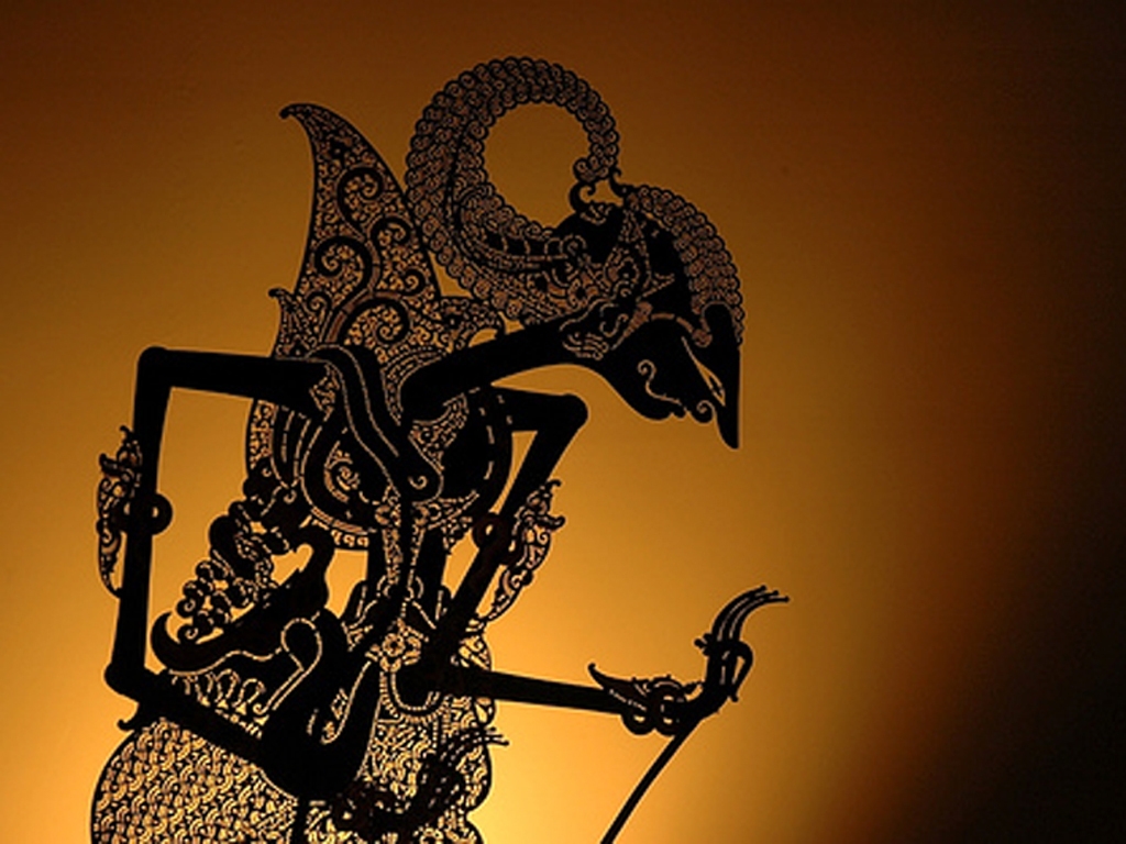 A black and white image of two intricately designed Wayang kulit puppets projected as shadows onto a screen during a performance.