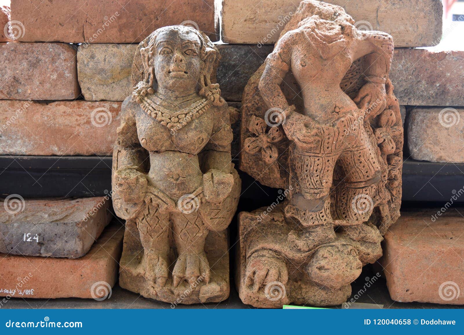 Two stone statues believed to be heirlooms from the Majapahit Kingdom, displayed in front of a brick wall.