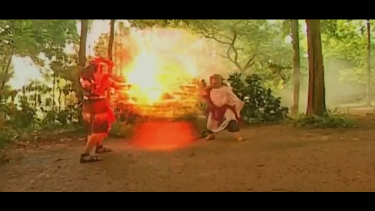 Still shot from a video showing two men in traditional Javanese attire engaged in a supernatural fight, with one man shooting fireballs from his hands at the other.
