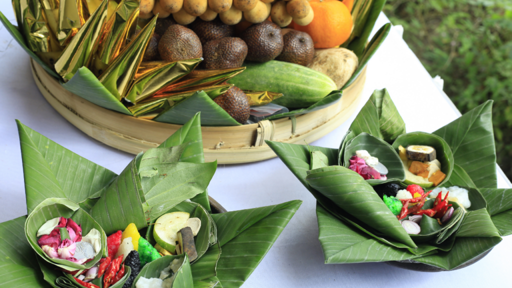 An image of offerings, including a tray with fruits and vegetables, and two smaller trays with flowers and other items, used in a Javanese ritual to honor and connect with their ancestors.