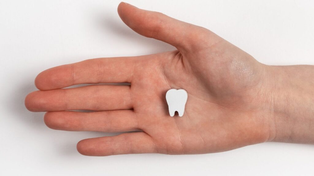 A cartoon tooth in the palm of a person's hand.